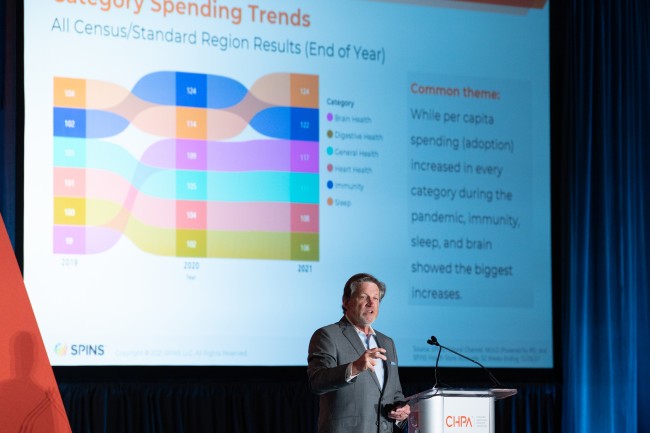 Man presenting at a conference with graphical slide in the background