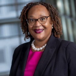 Adriainie Thomas headshot wearing black blazer and pink shirt