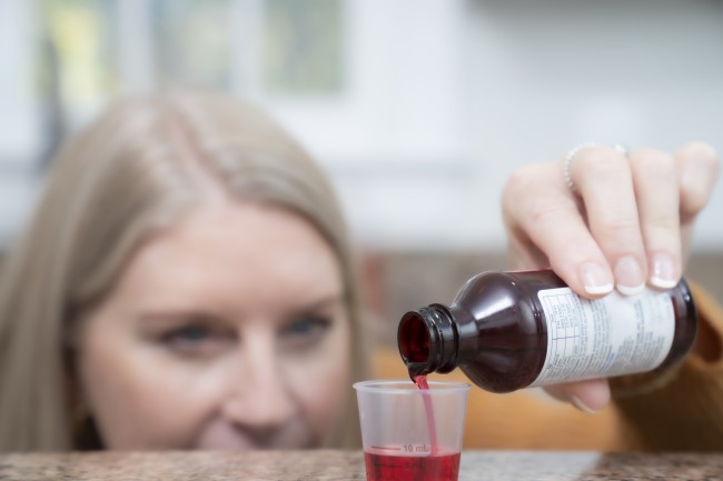 Blonde Caucasian/White woman measuring liquid medicine