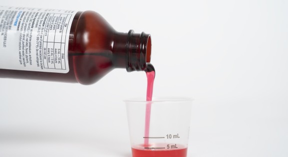 Liquid medicine being poured into a dosing cup