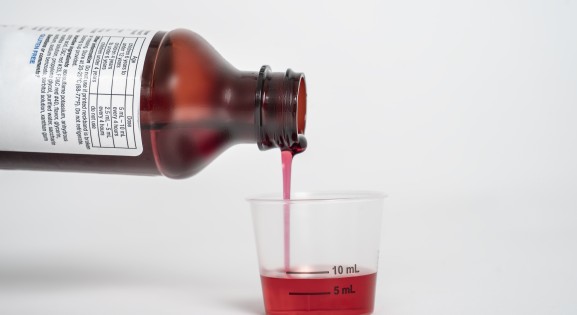 Liquid medicine being poured into a dosing cup