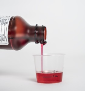 Liquid medicine being poured into a dosing cup
