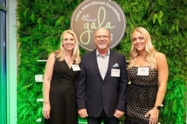 Two women and one man posing in front of Foundation Gala sign