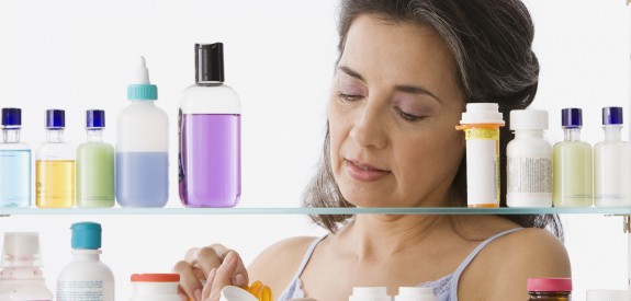 Hispanic woman measuring out medicine in front of a medicine cabinet