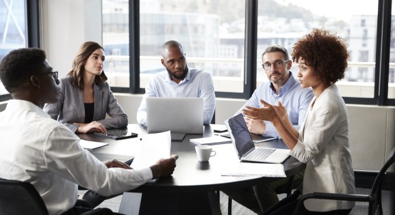 Millennial black businesswoman addressing colleagues at a corporate business meeting