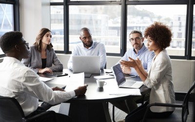 Millennial black businesswoman addressing colleagues at a corporate business meeting Millennial black businesswoman addressing colleagues at a corporate business meeting