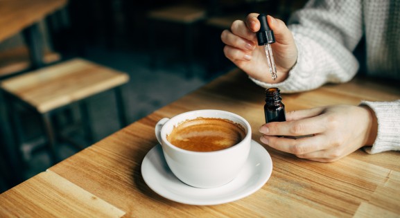 person adding CBD oil to a latte