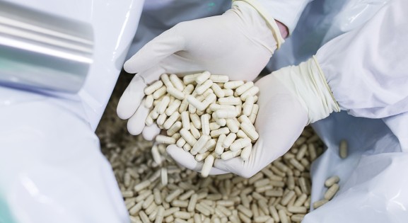 hands in sterile gloves holding manufactured white tablets