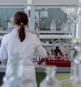 scientist with long dark hair in a lab facing away