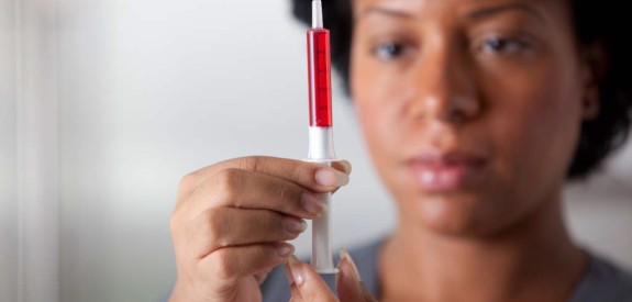 African American woman measuring medicine with dosing syringe