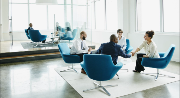 Group of Four Professionals in a Corporate Setting sitting in blue chairs